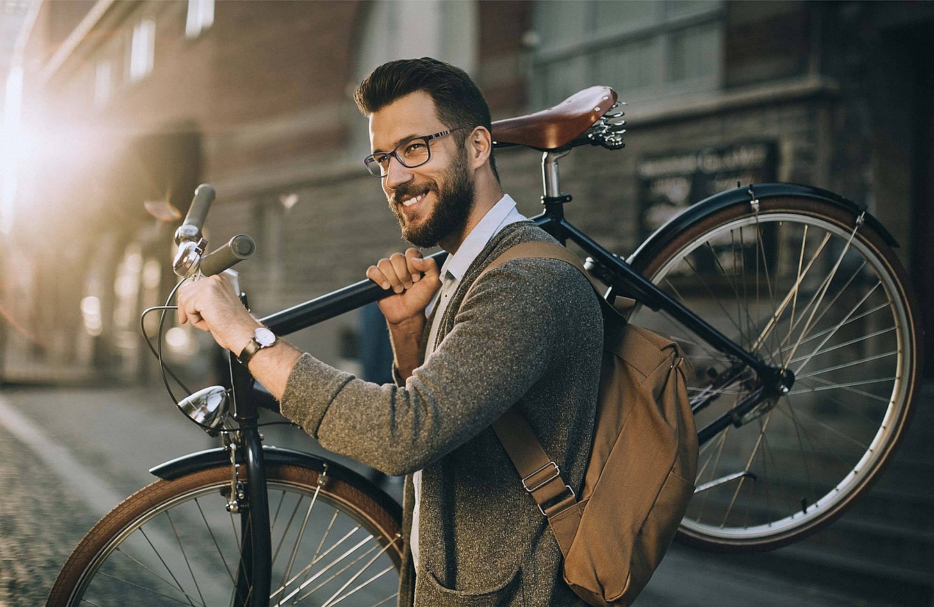 Mann mit Brille und Fahrrad in urbaner Umgebung
